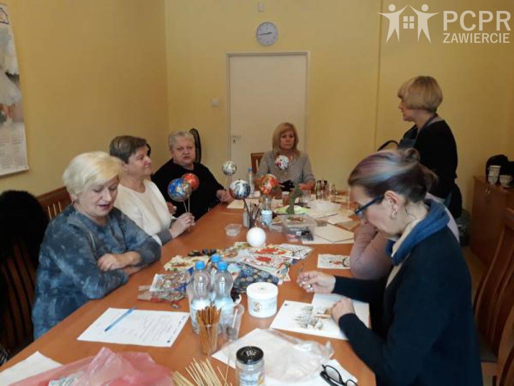 Zdjęcie: Grupa kobiet wykonuje ozdoby świąteczne siedząc przy stole zastawionym materiałami plastycznymi